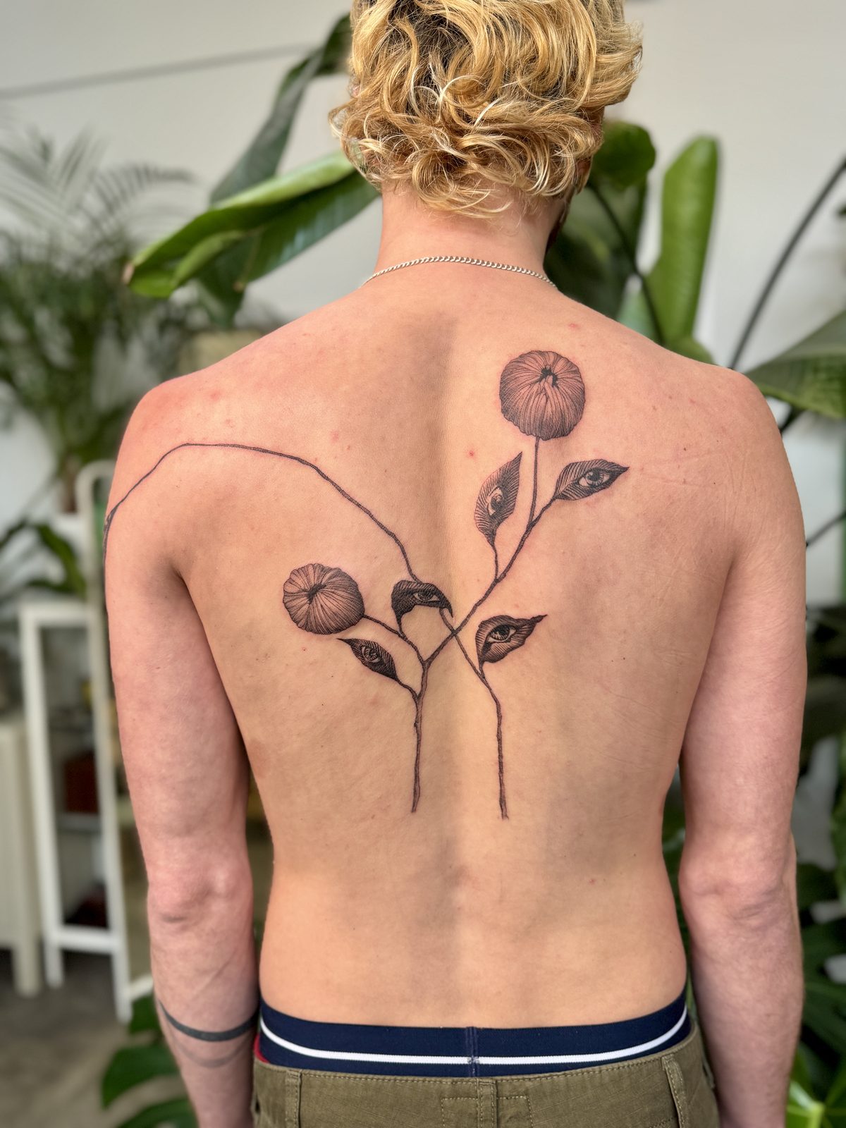 Abstract botanical back tattoo with eyes in the leaves, fine line, by Gosia, Bristol