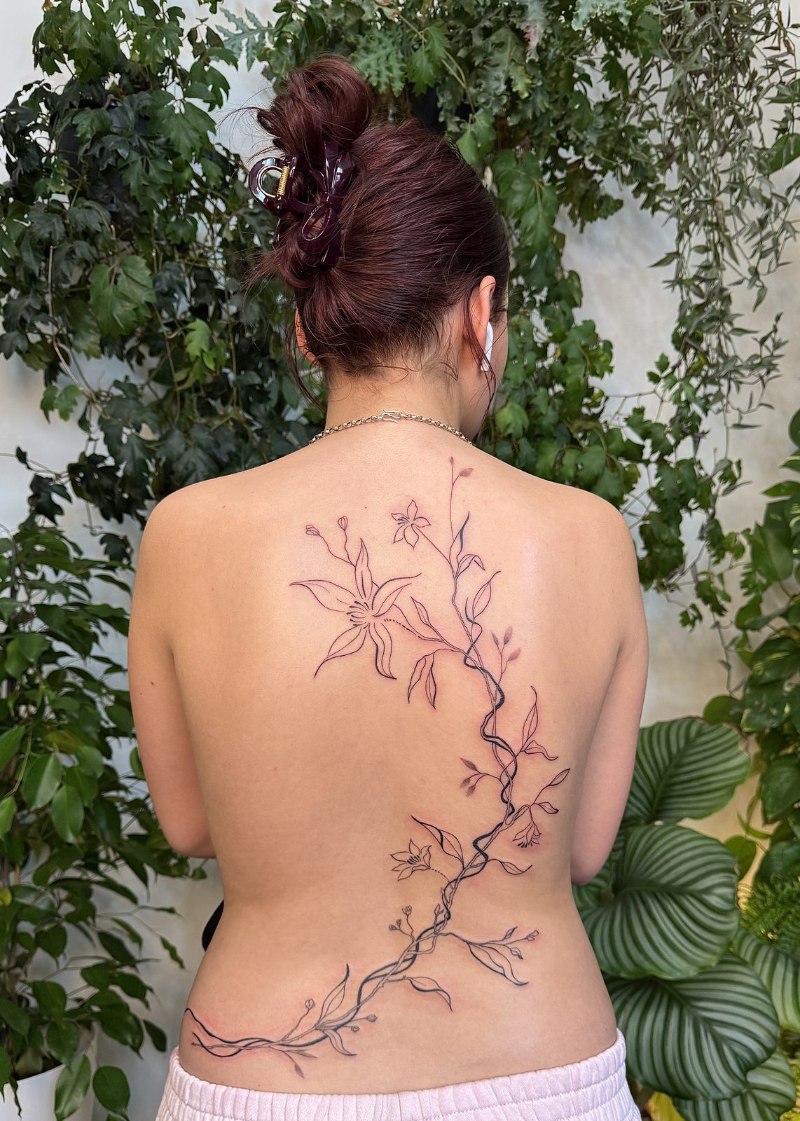 Fine-line floral back tattoo flowing up the spine, by Gosia, Bristol